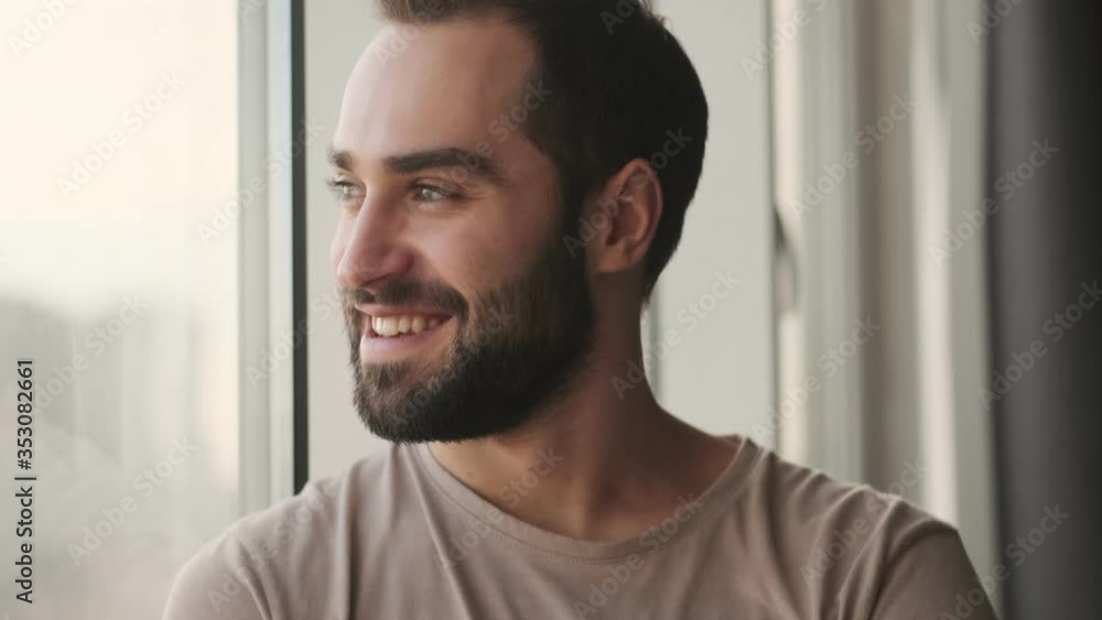 A handsome young man is looking to the window sitting at home A handsome young man is looking to the window sitting at home