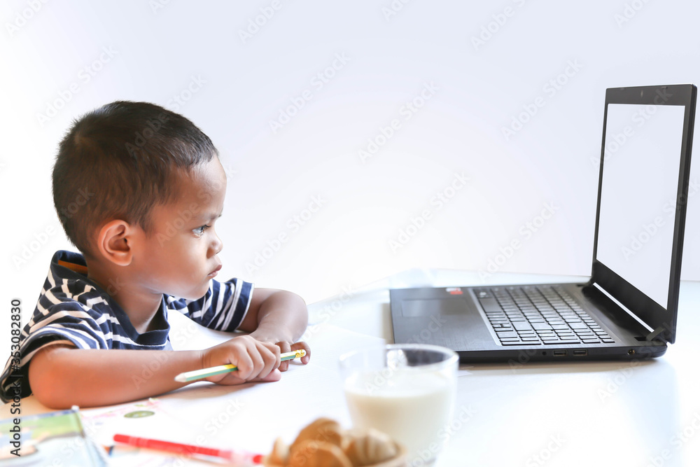 The little Asian boy studying online at home. Concept of online learning. The little Asian boy studying online at home. Concept of online learning.