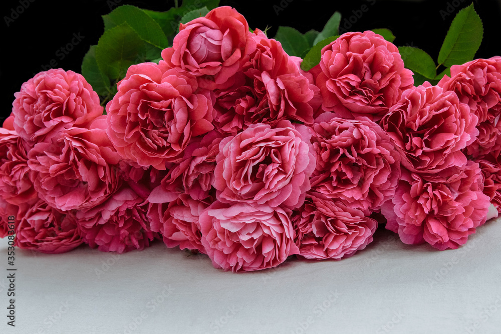 A large bouquet of pink roses lies on a white table with an empty space.