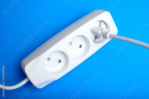 Electrical extension cord, plug and socket on a blue background. The concept of work on electrification.