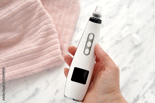 Vacuum blackhead remover in woman hand, cosmetic beauty procedure at home.