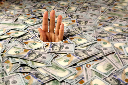 фотографія A hand sticks out of a mountain of dollars