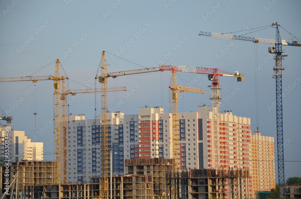 Inside place for many tall buildings under construction and cranes under a blue sky working on place with tall homes Inside place for many tall buildings under construction and cranes under a blue sky working on place with tall homes