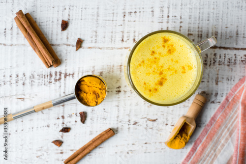 Golden milk with curcuma powder, Turmeric latte with spices on a white background, Hot healthy drink. Healthy ayurvedic drink. Detox beverage with spices for vegans.