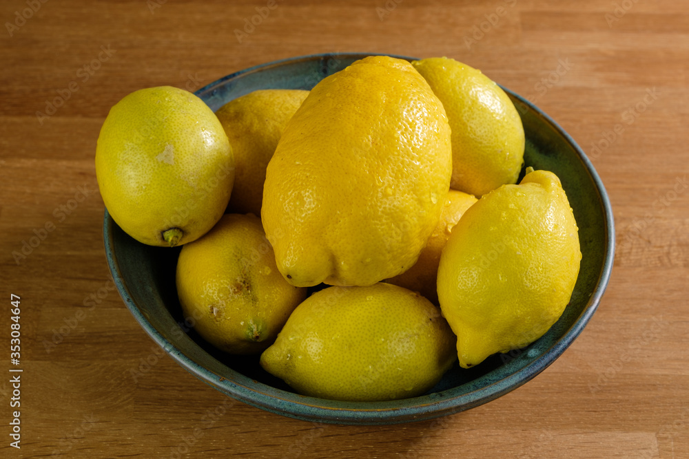 Obstschale: Eine Schale mit mehreren frischen gelben Zitronen auf einem Holz-Hintergrund
