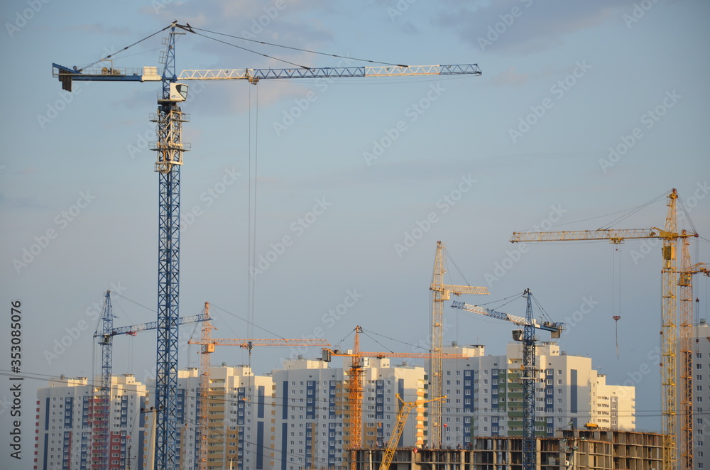 Inside place for many tall buildings under construction and cranes under a blue sky working on place with tall homes Inside place for many tall buildings under construction and cranes under a blue sky working on place with tall homes