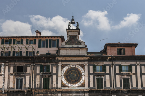 Old astronomical clock on the facade of the building. Brescia, Italy. Soft focus, blurry background.