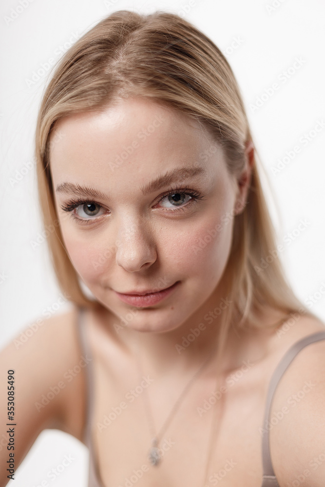 pretty caucasian girl with naked shoulders looking at camera. beauty portrait, close up. beautiful woman with perfect clean skin on white studio background. soft focus on her face