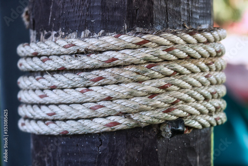 This unique photo shows a white red rope wrapped around a wooden post. The picture was taken in Hua Hin Thailand