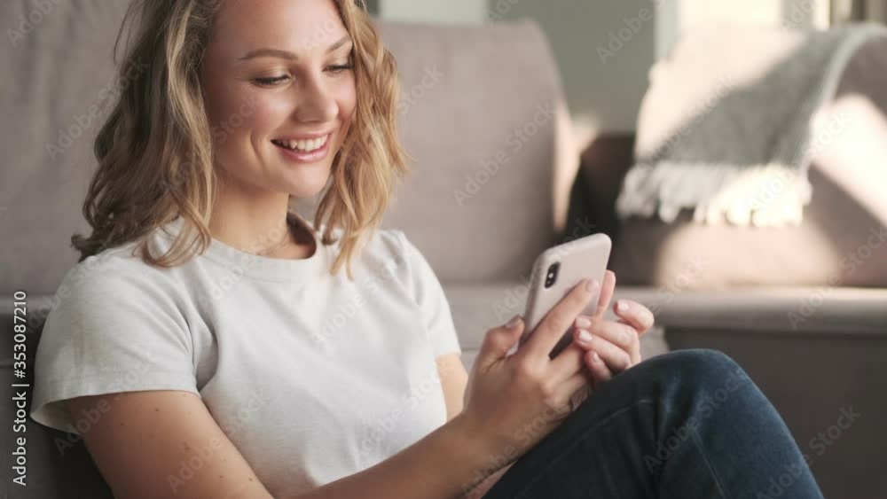 Young positive woman indoors at home using mobile phone Young positive woman indoors at home using mobile phone