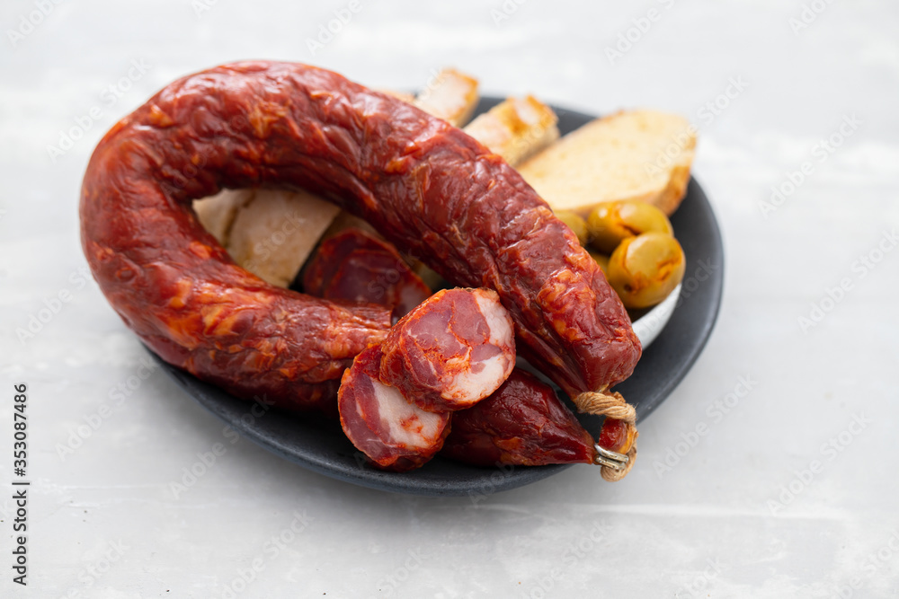 Fototapeta premium portuguese smoked sausage, olives and corn bread broa on ceramic background