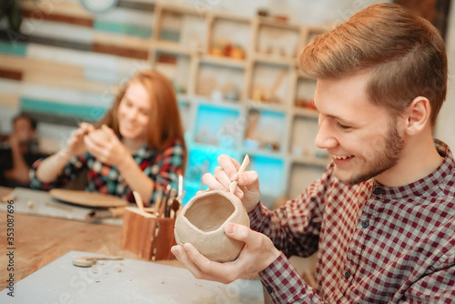 Young man and woman works in pottery and laughs. Sculpting from clay.