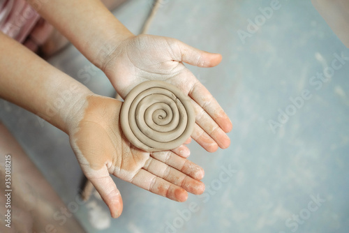 Kid's hands hold clay product. New hobby. Pottery workshop. © Danila Shtantsov