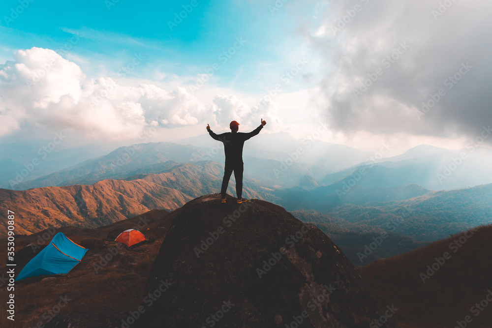 Obraz premium Silhouette of man hold up hand on the peak of mountain,success concept