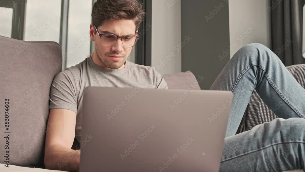 Concentrated man indoors at home using laptop computer Concentrated man indoors at home using laptop computer