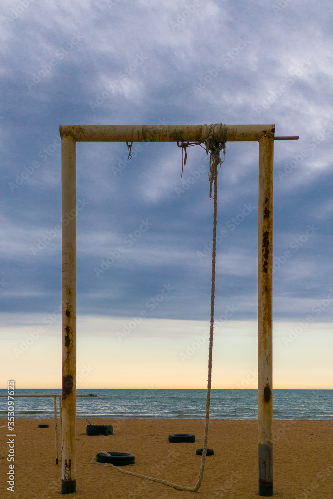 Tall turnstile on the beach with rope to pull up. Blue sky and ocean on background. Tall turnstile on the beach with rope to pull up. Blue sky and ocean on background.