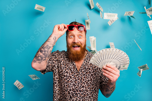 Photo of excited macho guy hold fan usa bucks good mood money luxury rich person dollars fall income lottery cashback wear leopard shirt sun specs isolated blue background photo