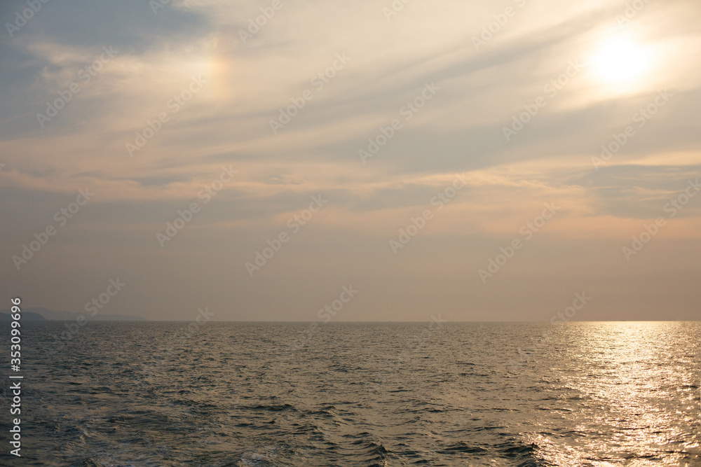 Naklejka premium Natural background. The sun goes down to the horizon above the sea or ocean. Sunset over the water.