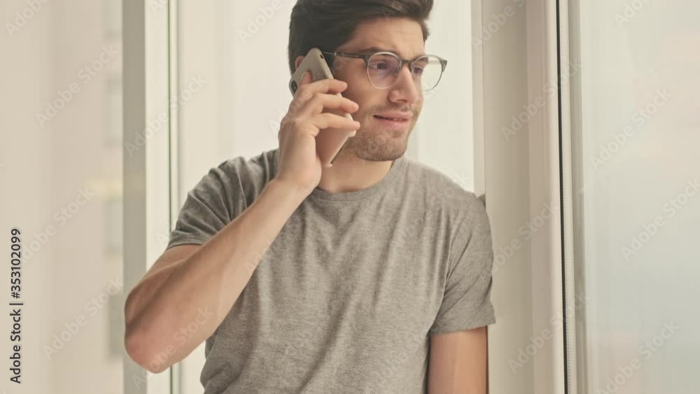 Concentrated man indoors at home talking by mobile phone Concentrated man indoors at home talking by mobile phone