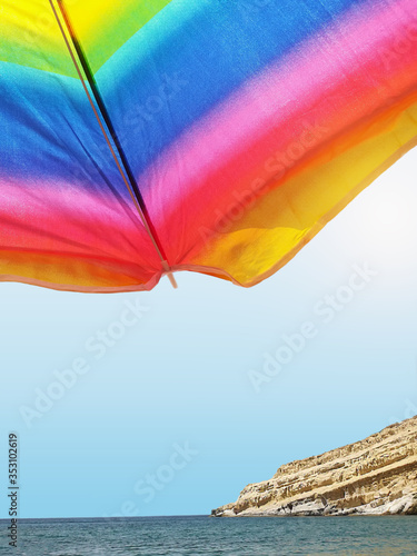 view on matala beach from under a colorful umbrella