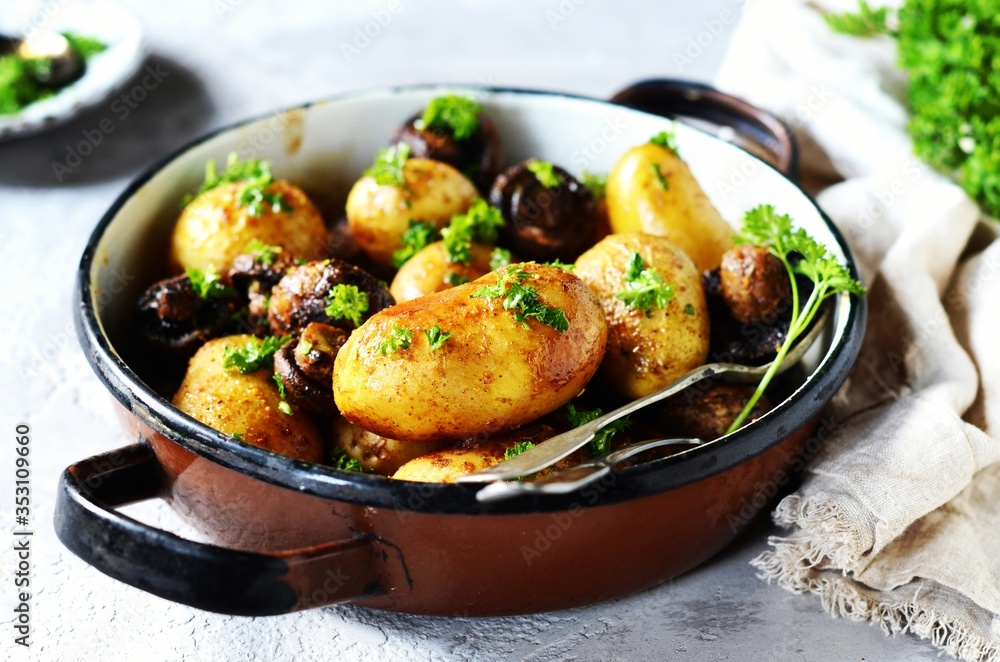 Baked young potatoes with mushrooms in a bowl on a gray background Baked young potatoes with mushrooms in a bowl on a gray background