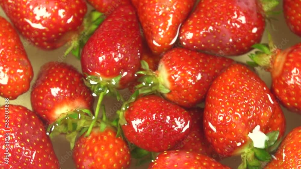 Slow motion rotation of juicy strawberries. Top view, Rotation 360 degrees, Extreme close up.spray water Slow motion rotation of juicy strawberries. Top view, Rotation 360 degrees, Extreme close up.spray water
