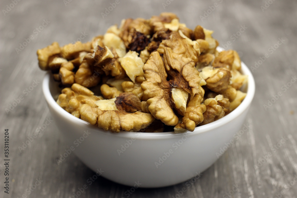 walnut kernels in a bowl on a gray background walnut kernels in a bowl on a gray background