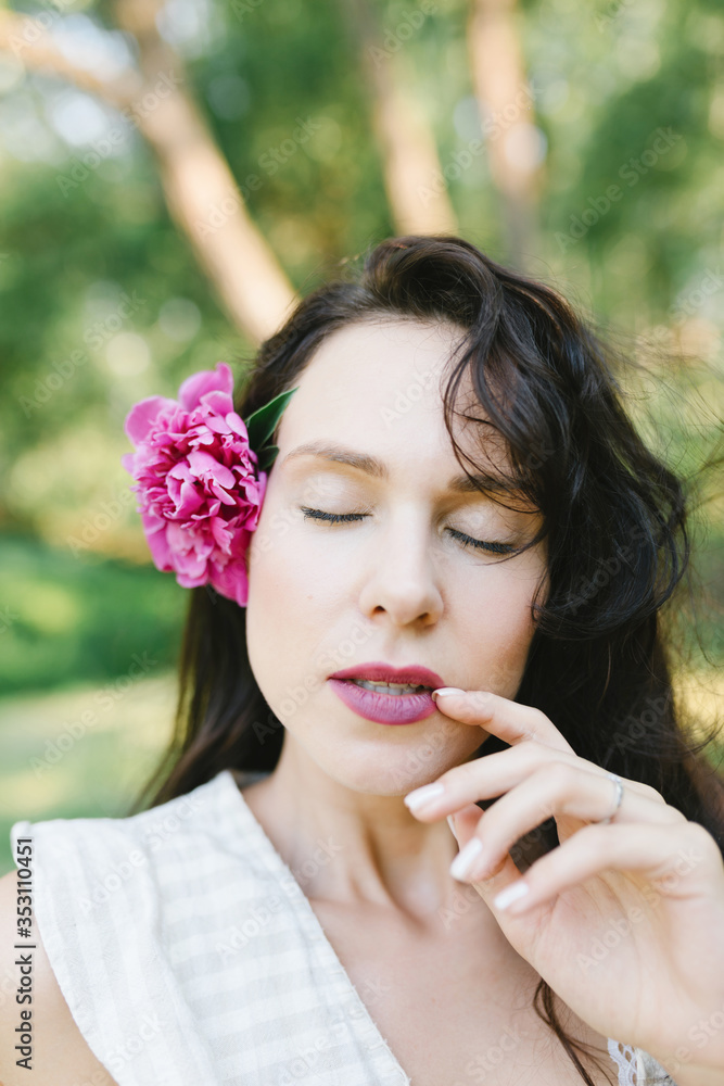 Girl and a flower in her hair. Brunette and peony in the hair. Portrait of a beautiful young woman. Girl and a flower in her hair. Brunette and peony in the hair. Portrait of a beautiful young woman.