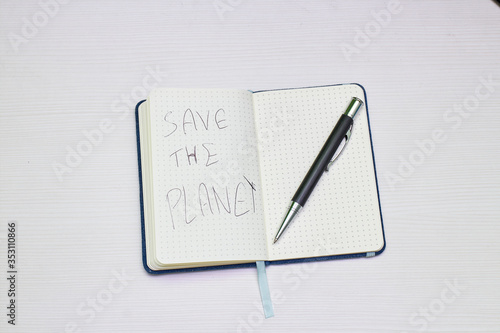 notebook with message to save the planet and black pen