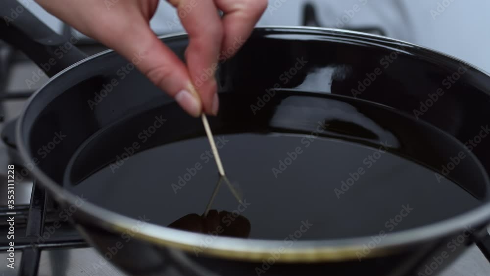 Boiling Stick Example A close-up look of a woman's hand checking the oil temperature by ...