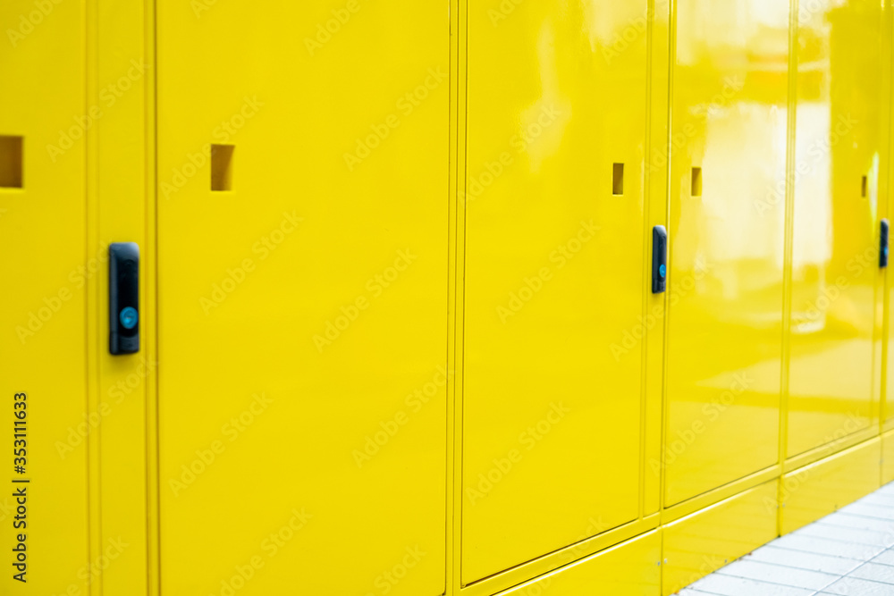 Fototapeta premium Yellow wall and Electrical control panel beside the yellow locked locker for students at university that have number on locker and keys for each students. Decoration and design. close up