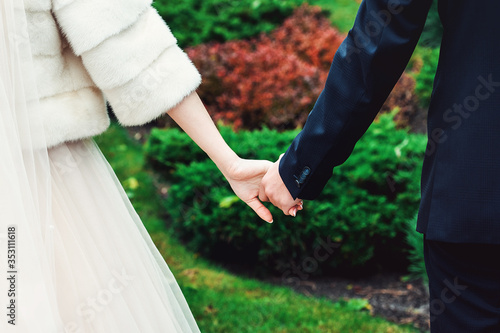 Young couple holding hands. Wedding day. Outdoors