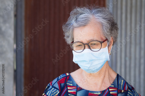 Portrait of an elderly woman wearing a face mask with a worried.