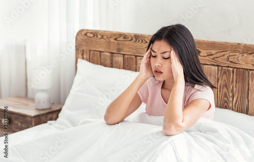 Chinese Woman Having Headache Suffering From Pain Sitting In Bed