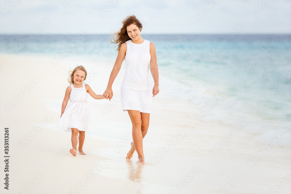 Mother and little daughter walking on beach on Maldives at summer vacation