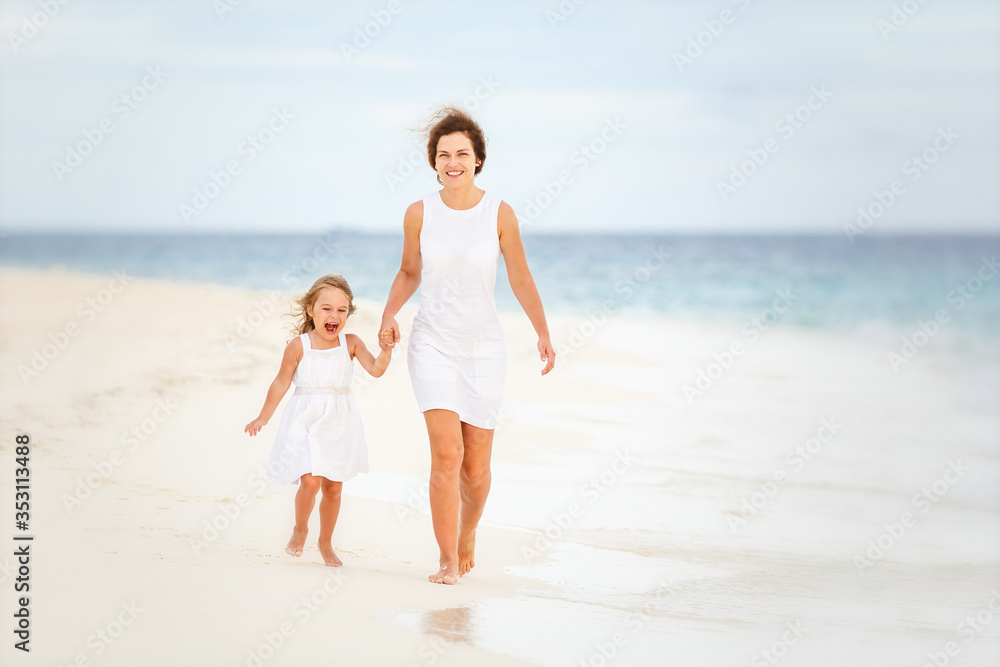 Mother and little daughter walking on beach on Maldives at summer vacation