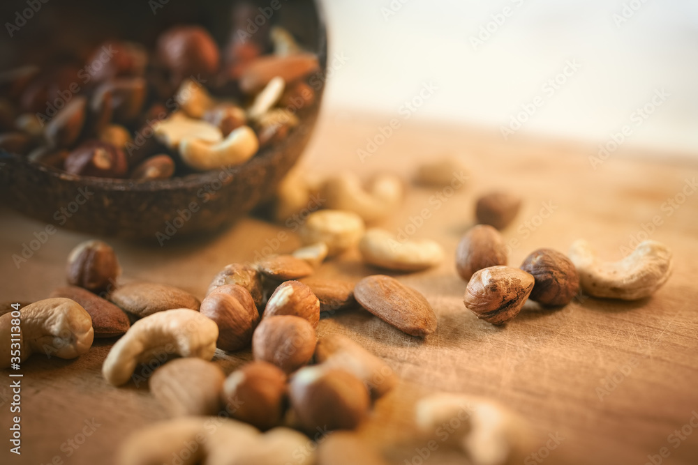 Nuts spilled from coconut bowl on wooden cutting board. Nuts spilled from coconut bowl on wooden cutting board.