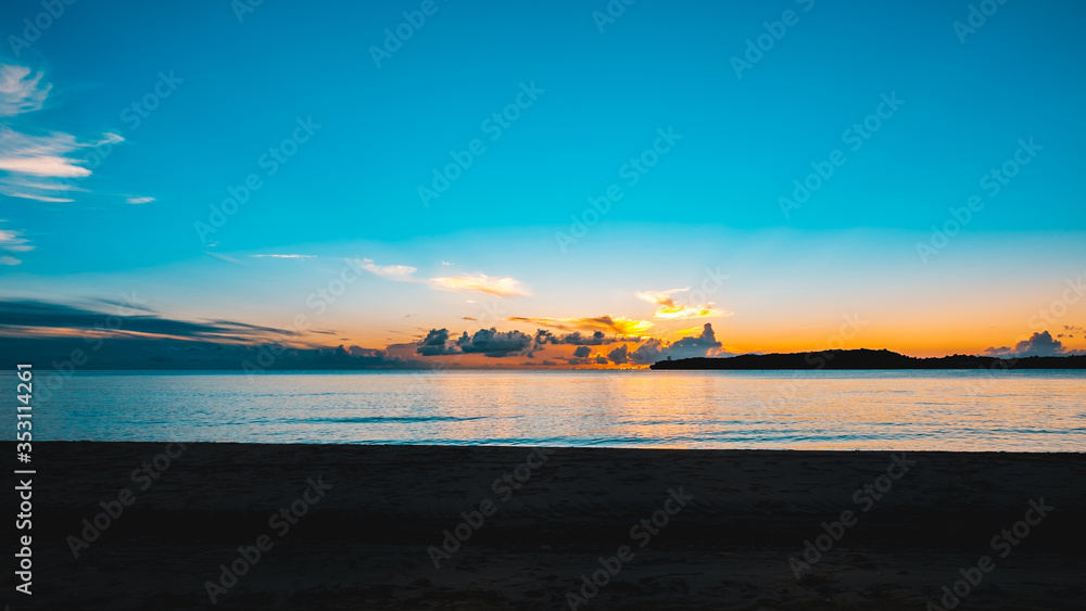 Obraz premium A beautiful sunset with a colorful bright blue sky at a tropical beach.