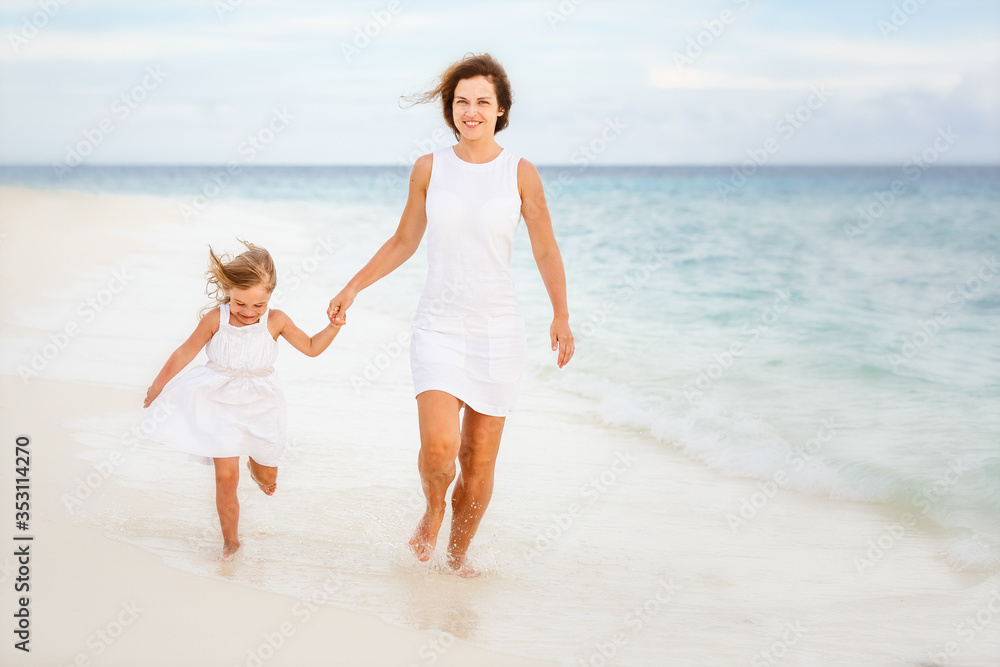 Mother and little daughter running on a beach on Maldives at summer vacation Mother and little daughter running on a beach on Maldives at summer vacation