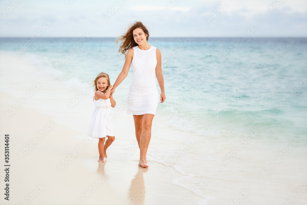 Mother and little daughter walking on beach on Maldives at summer vacation