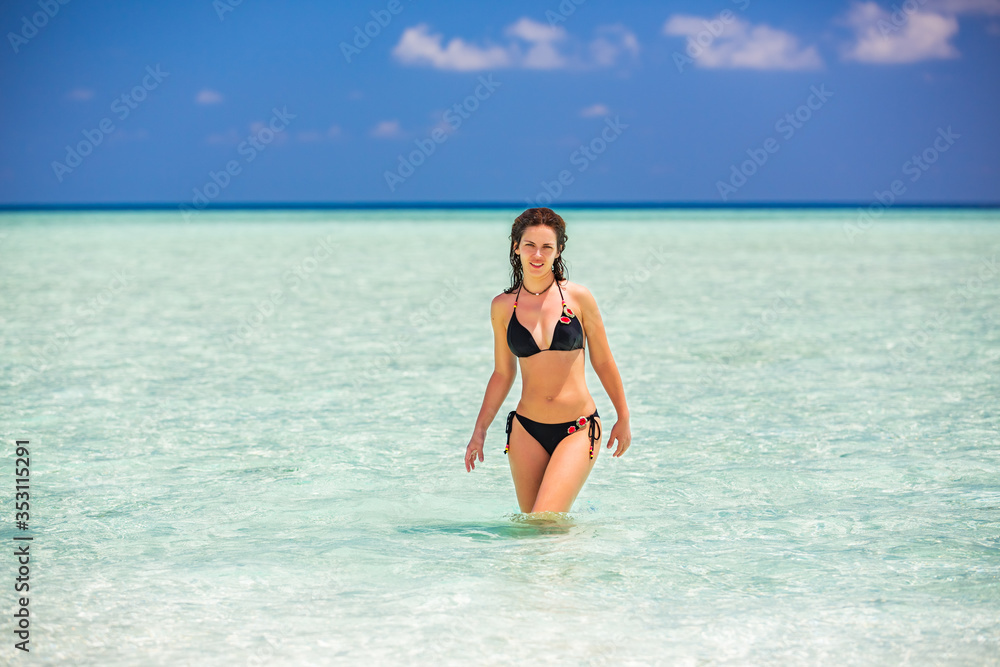 Happy young woman in bikini enjoing the beautiful ocean beach on Maldives