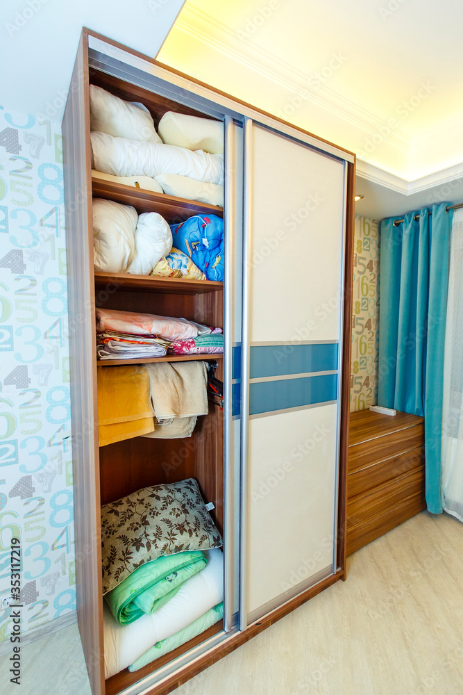 open Built-in wardrobe with bedding. There is a chest of drawers next to it open Built-in wardrobe with bedding. There is a chest of drawers next to it