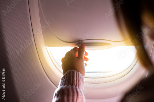 Woman's hand opening a plane window. Concept of air travel and passenger comfort.
