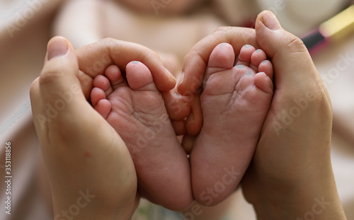 Bare feet baby in the hands of mom. The heels and toes of the baby