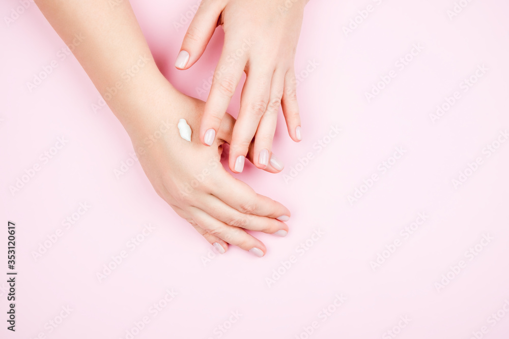 Delicate female hands on a pink background. Beautiful Nude manicure and a little cream on your hands