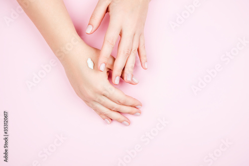 Delicate female hands on a pink background. Beautiful Nude manicure and a little cream on your hands © NS