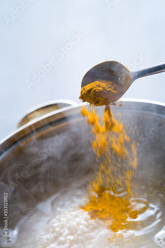 Someone adding the turmeric to the cooked rice