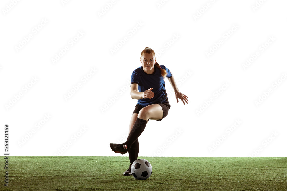 Obraz premium Young female soccer or football player with long hair in sportwear kicking ball for the goal, training on white studio background. Concept of healthy lifestyle, professional sport, motion, movement.