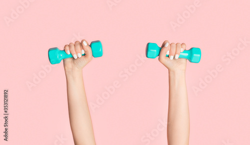 Young girl lifting dumbbells on pink background, closeup of hands. Panorama photo