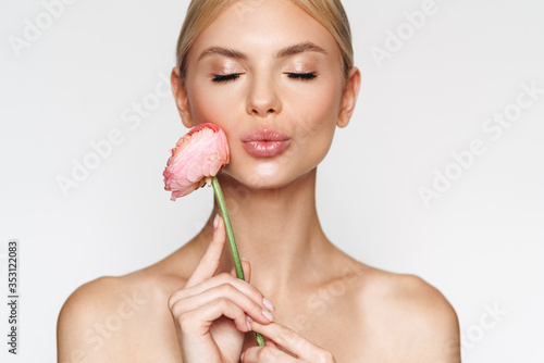 Fotografija Image of alluring shirtless woman holding flower and making kiss lips